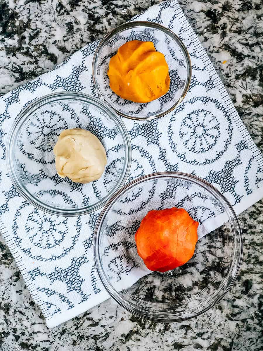 Boules de pâte jaune, orange et naturelle pour les biscuits en forme de bonbons de maïs.