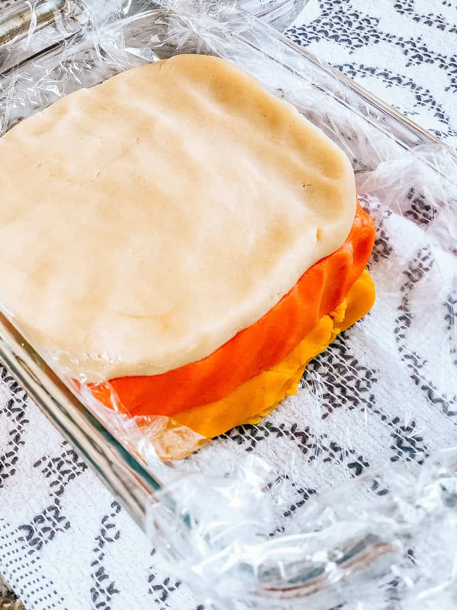 Pâte de biscuits superposée blanche, jaune et orange dans un moule à pain.