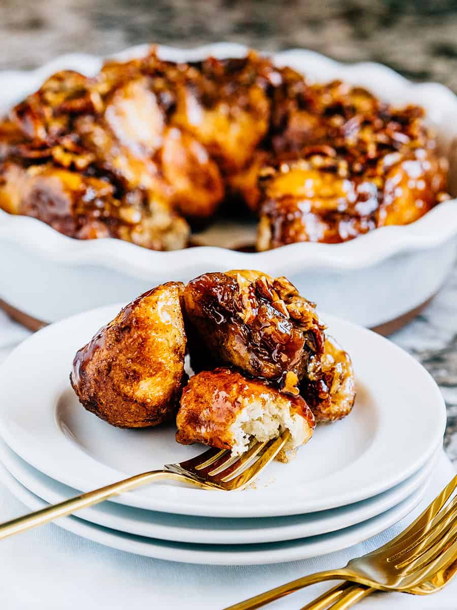 Une assiette avec des morceaux de monkey bread et le moule en arrière-plan.