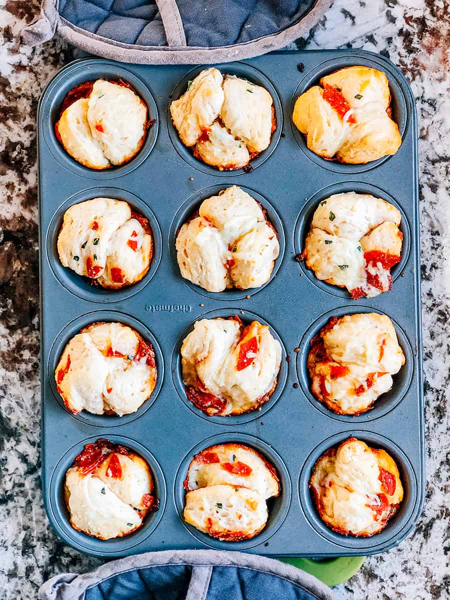 Des muffins à pizza à déchirer fraîchement cuits, encore dans les moules à muffins.