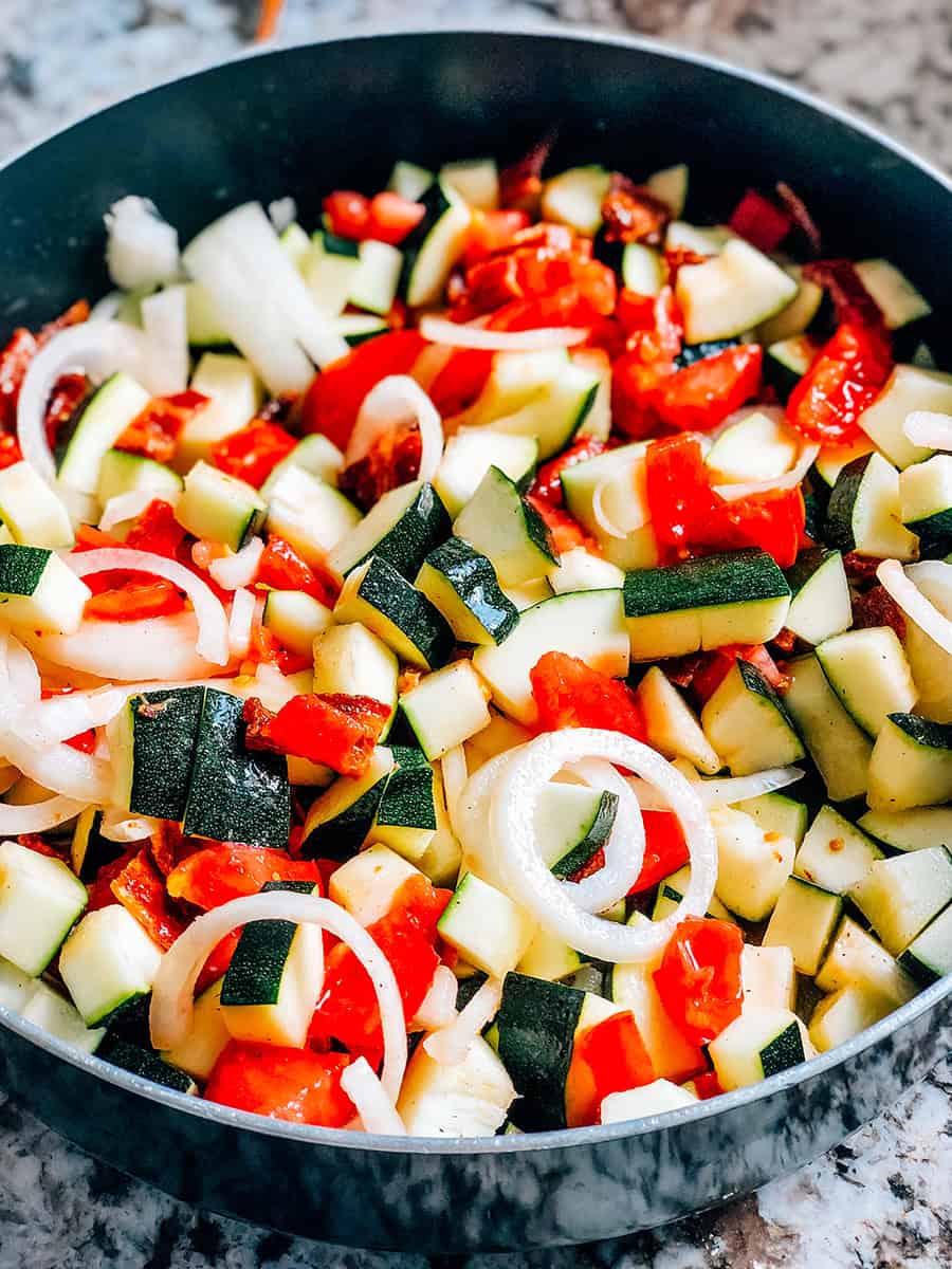 Zucchini à la poêle mélangé et prêt à être cuit jusqu'à ce que les légumes soient tendres.