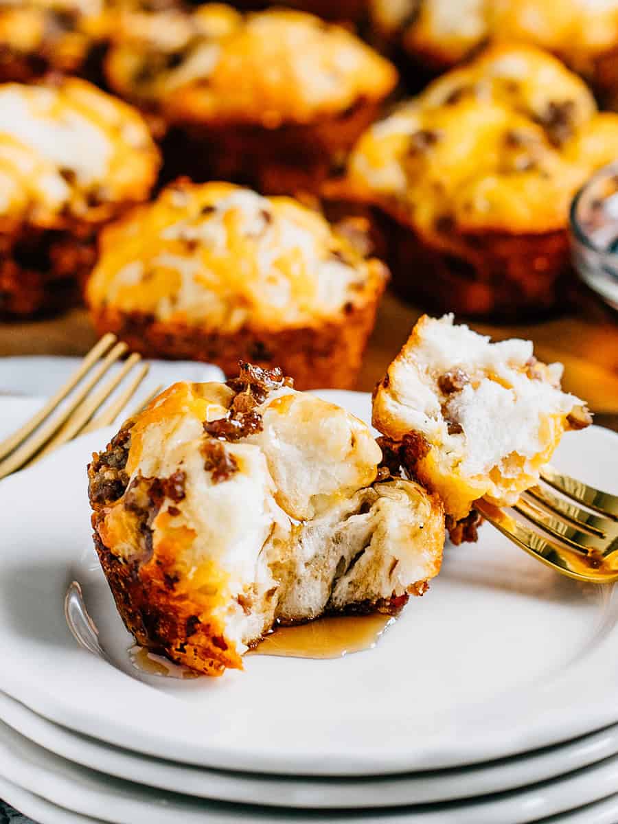 Un gros plan d'un muffin au petit-déjeuner avec saucisse recouvert de sirop à crêpes. Ils sont sucrés, légers et moelleux avec une bonne dose de protéines et de fromage : un excellent petit-déjeuner pour des enfants en mouvement !