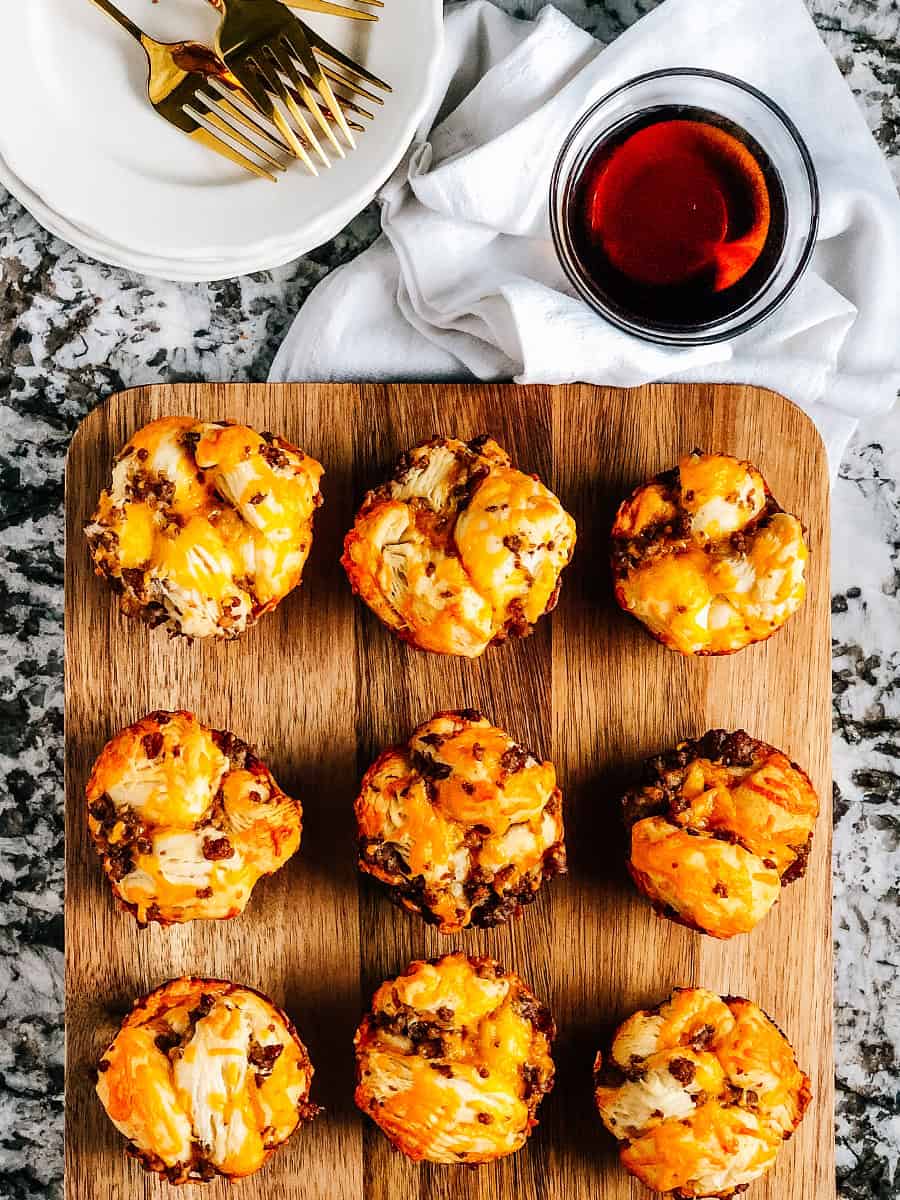 Une vue d'ensemble de muffins au petit-déjeuner savoureux sur une planche de service avec du sirop sur le côté pour tremper.