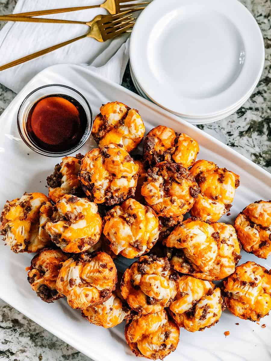 Des muffins au petit-déjeuner avec saucisse empilés sur une assiette de service avec une sauce à tremper à crêpes sur le côté. C'est l'idée de petit-déjeuner parfaite à manger avec les mains.