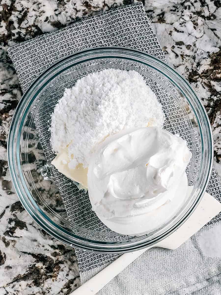 Fromage à la crème ramolli, Cool Whip et sucre en poudre dans un bol de mélange