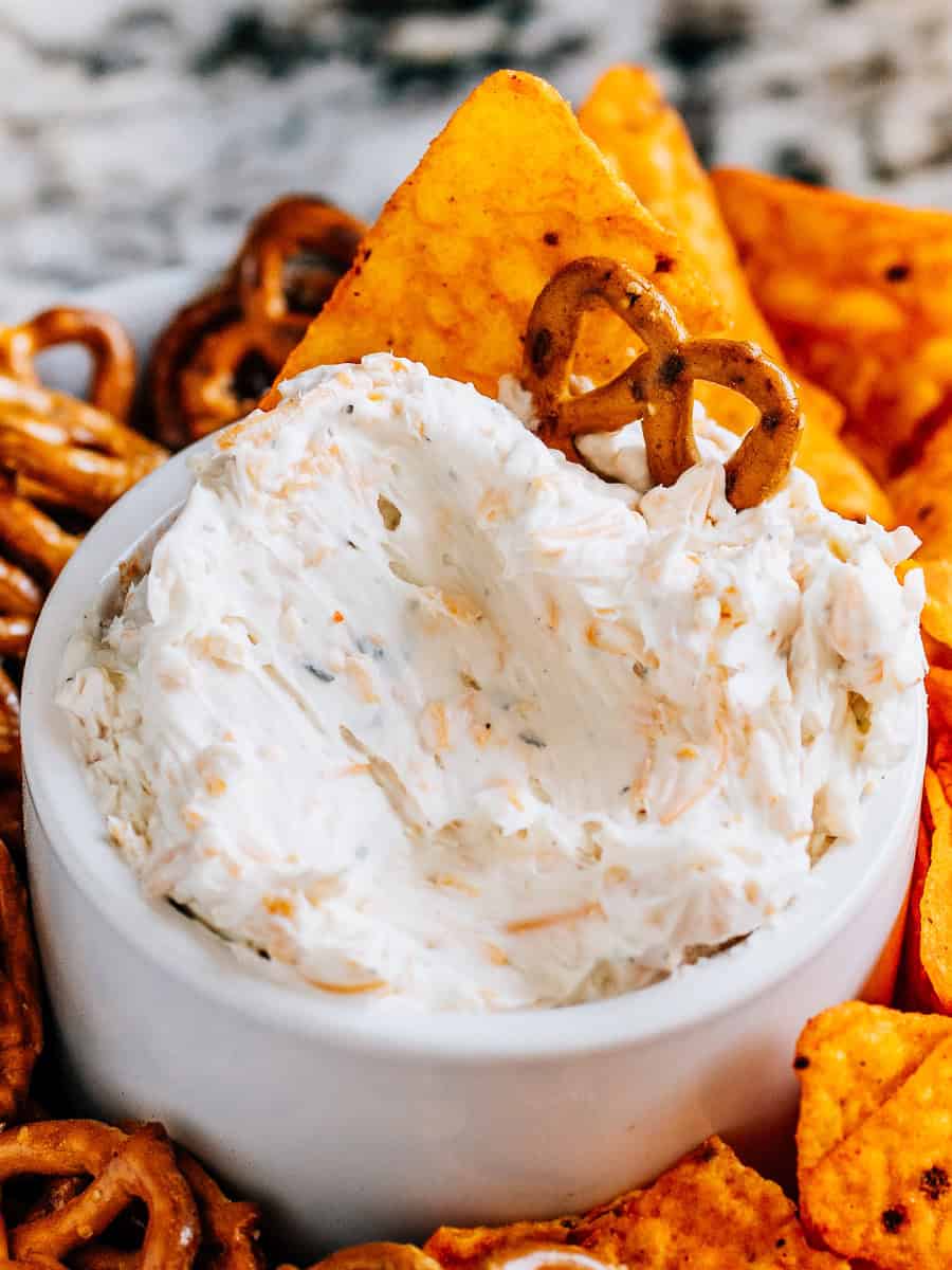 Trempette crémeuse au fromage à la bière Ranch avec un mini bretzel tordu et un dorito planté dedans, parfait pour les collations le jour du match.