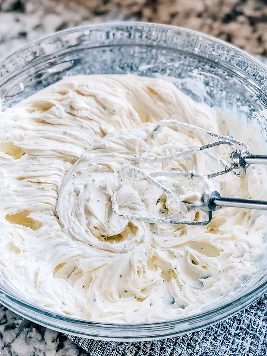 Fromage à la crème, assaisonnement Ranch et bière mélangés dans un bol en verre.