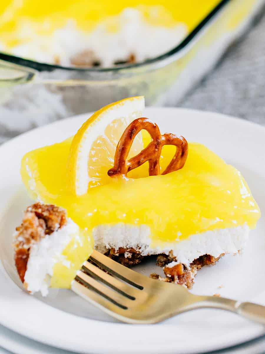 Une fourchette pleine de dessert au bretzel citron reposant sur l'assiette devant une portion.