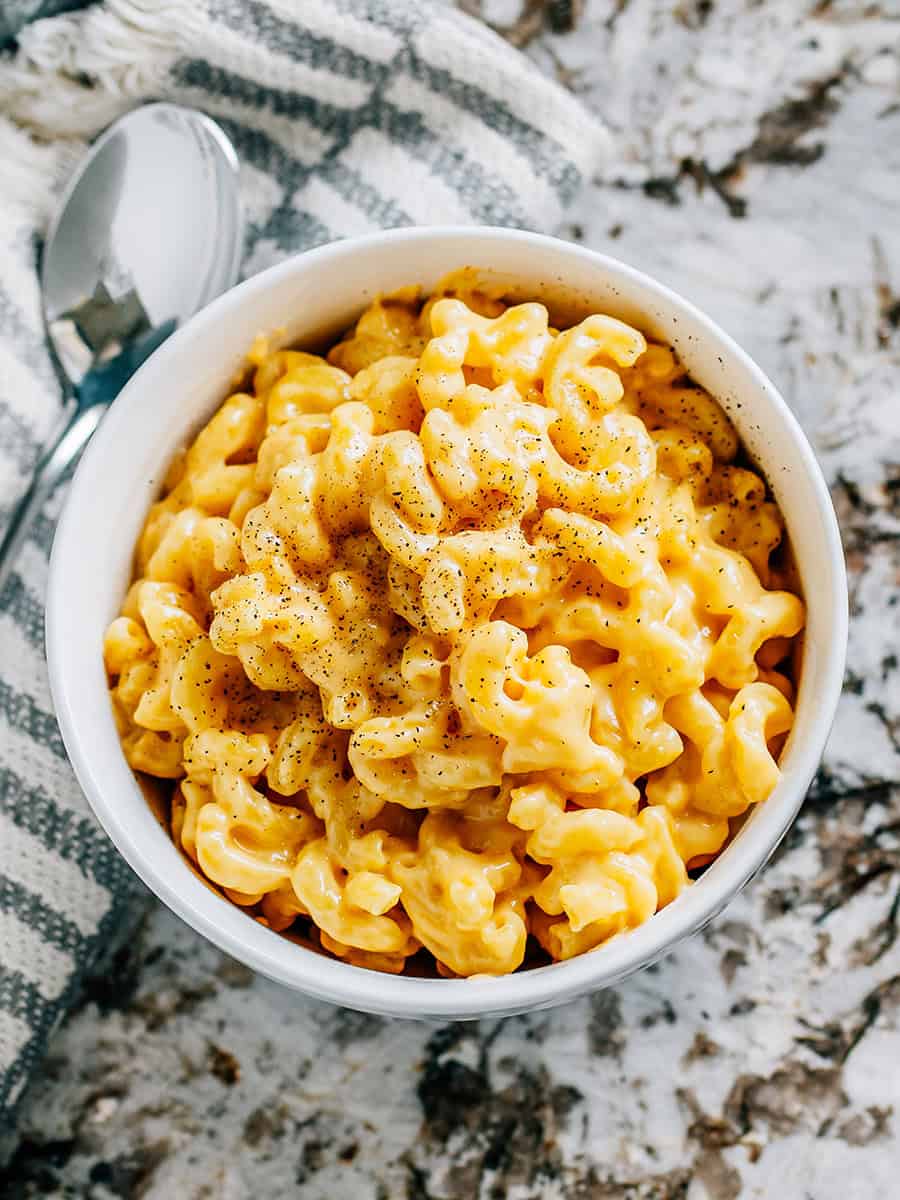 Un bol terminé de macaroni au fromage crémeux fait maison avec une pincée de poivre noir sur le dessus.