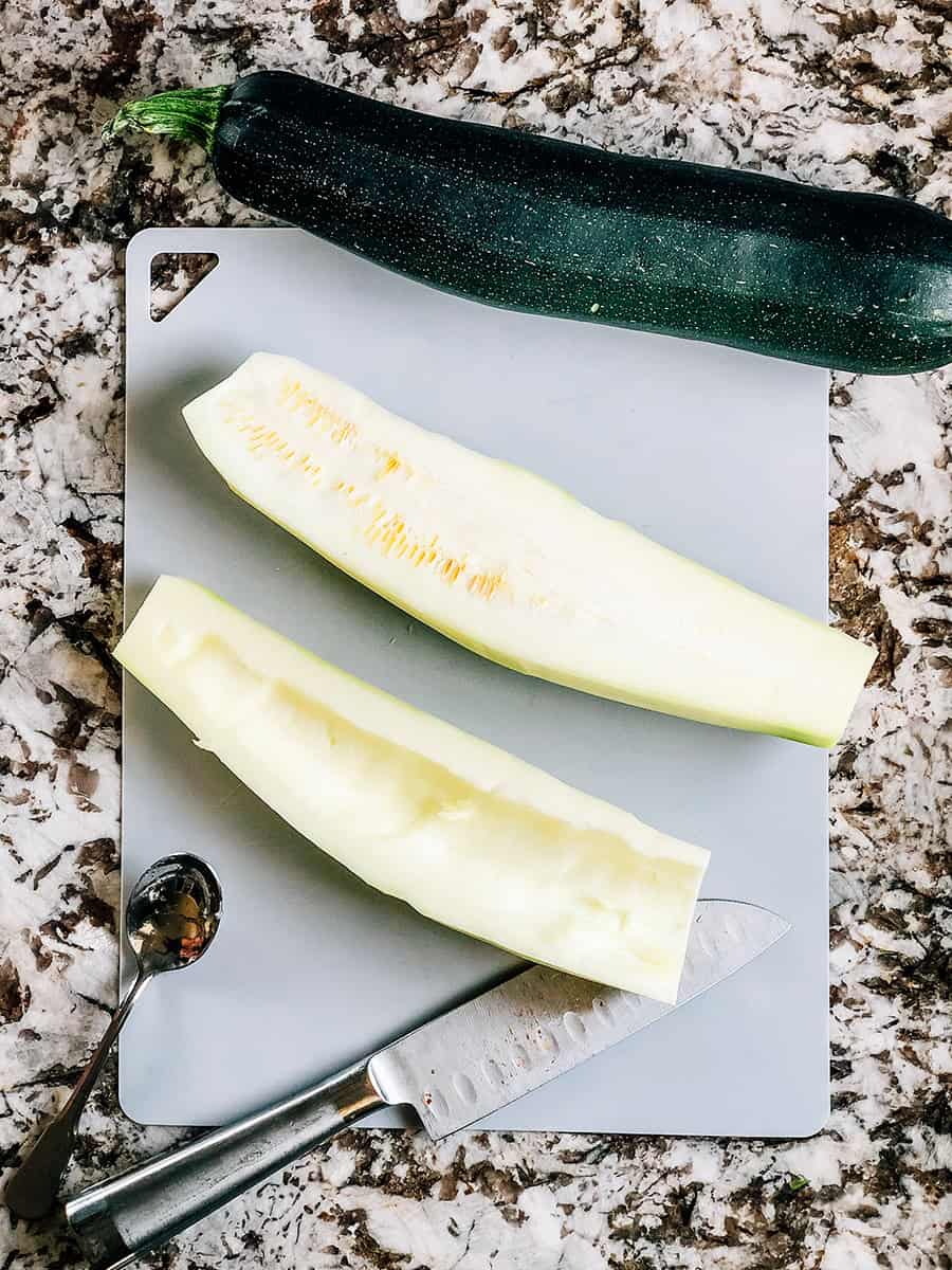 Courgettes sur une planche à découper ouvertes et l'une des côtés a les graines retirées.