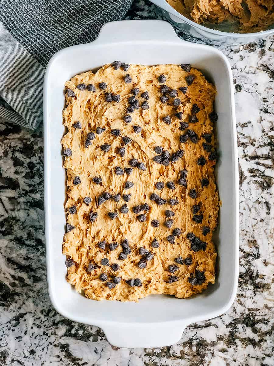 Pépites de chocolat semi-sucré généreusement parsemées sur la couche de pâte à cookie.