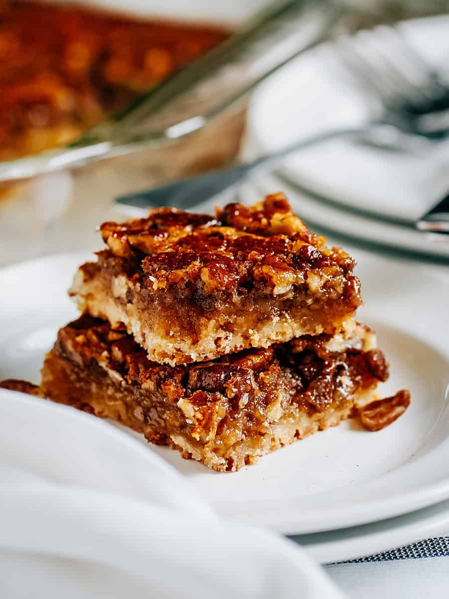 Deux barres de tarte aux pacanes empilées montrant la croûte friable, la garniture sucrée et les pacanes caramélisées de ces incroyables barres de tarte aux pacanes.