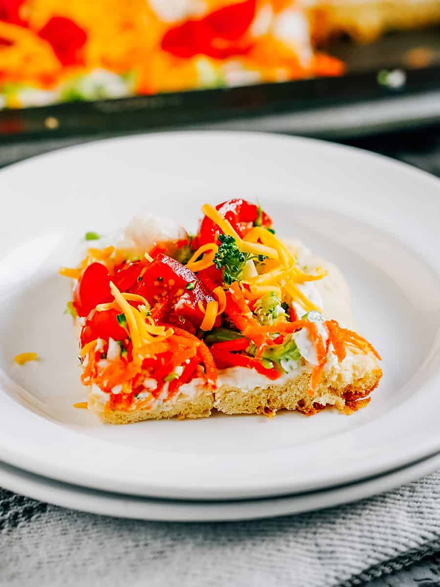 Morceau de pizza légumes avec brocoli, carotte, tomate et fromage sur une assiette.