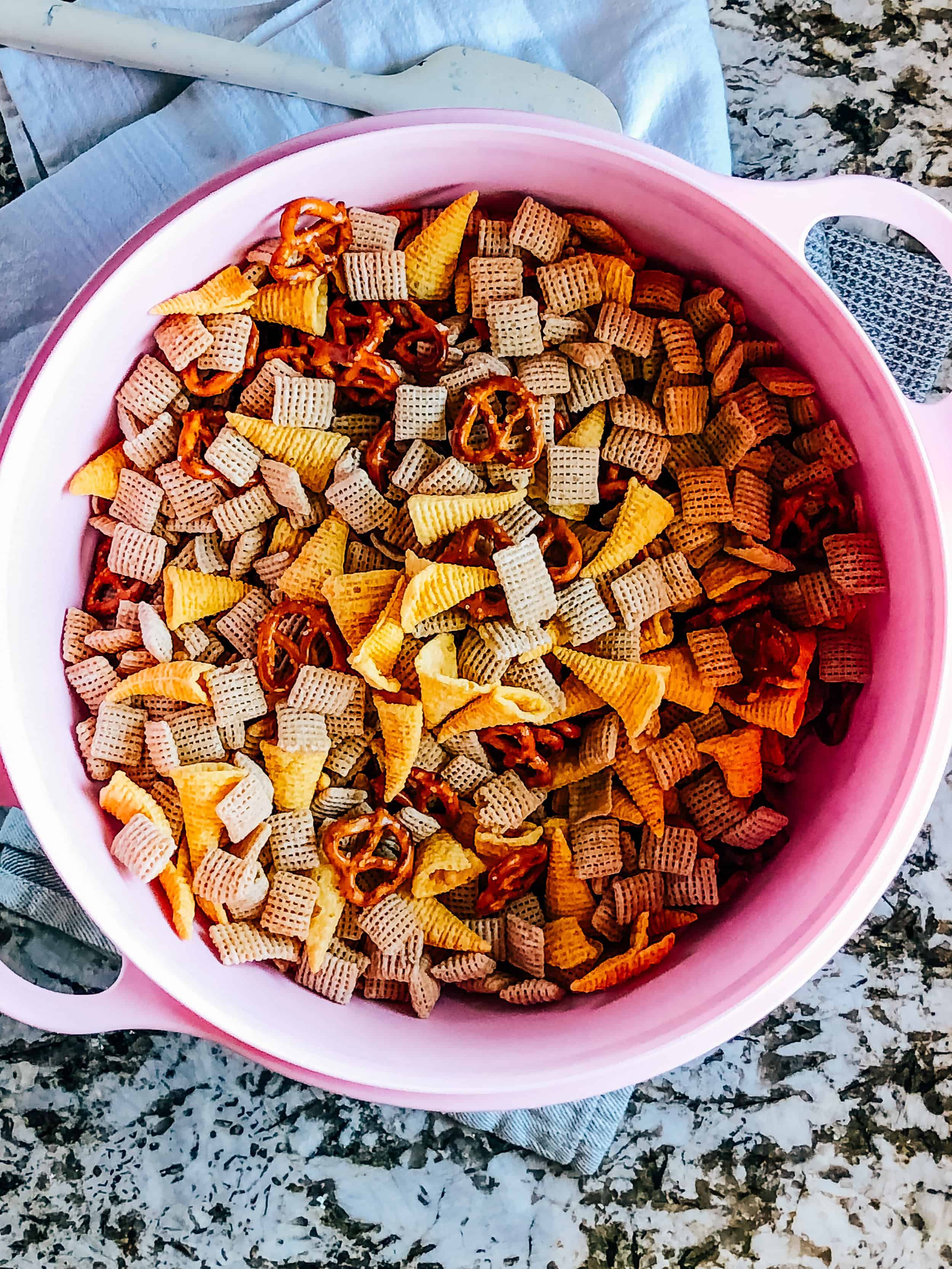 Tossed Bugles, rice chex, and pretzel twists in a bowl.