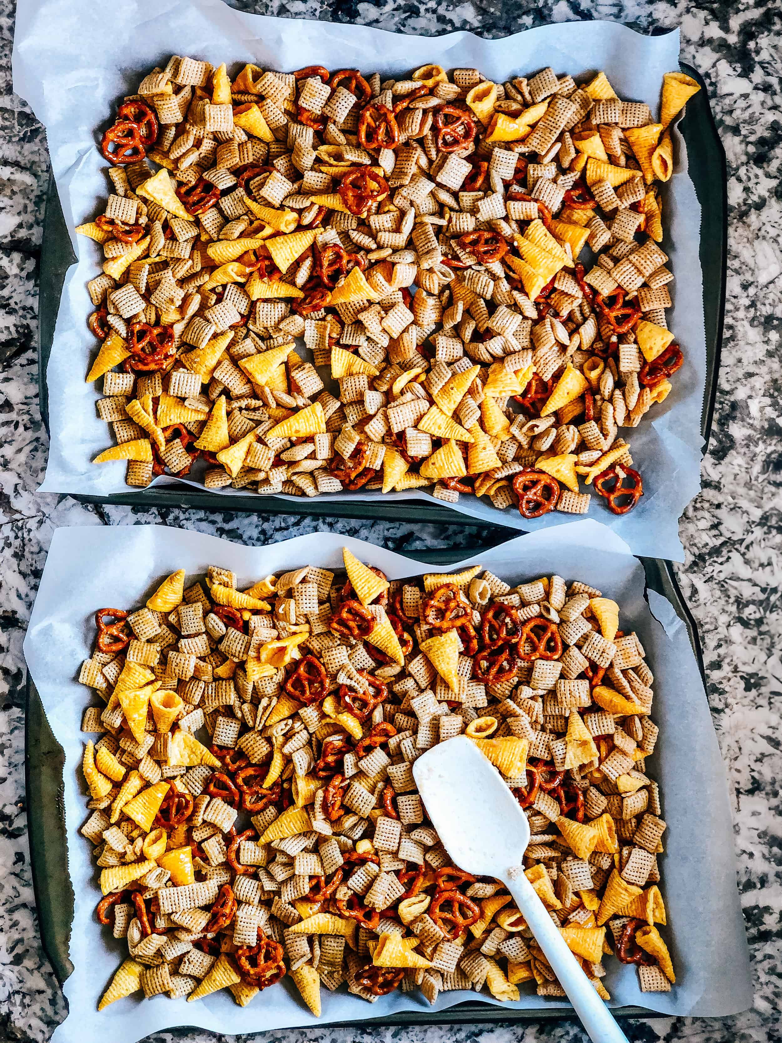 The brown sugar sauce coated rice squares, pretzels and Bugles spread evenly over large parchment paper lined baking sheets.