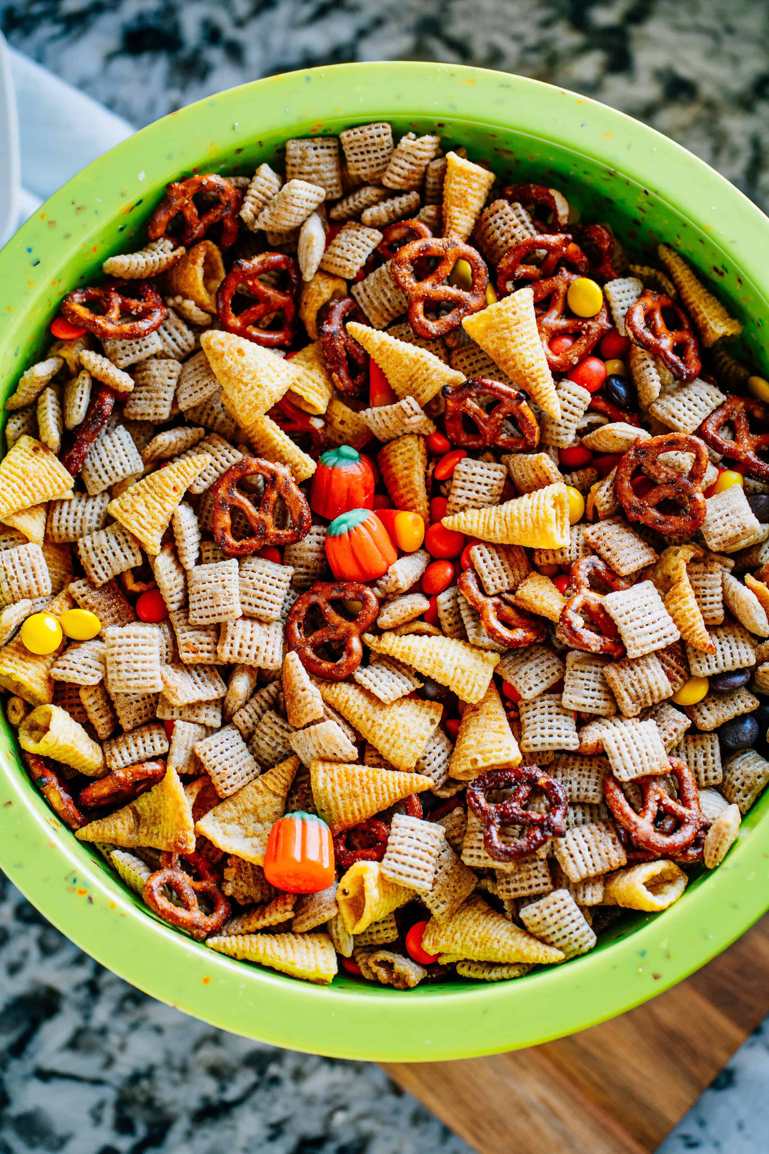 Tossed and completely combined snack mix with rice squares, Bugles, pretzel twists, candy corn, candy pumpkins, and Reese's Pieces.