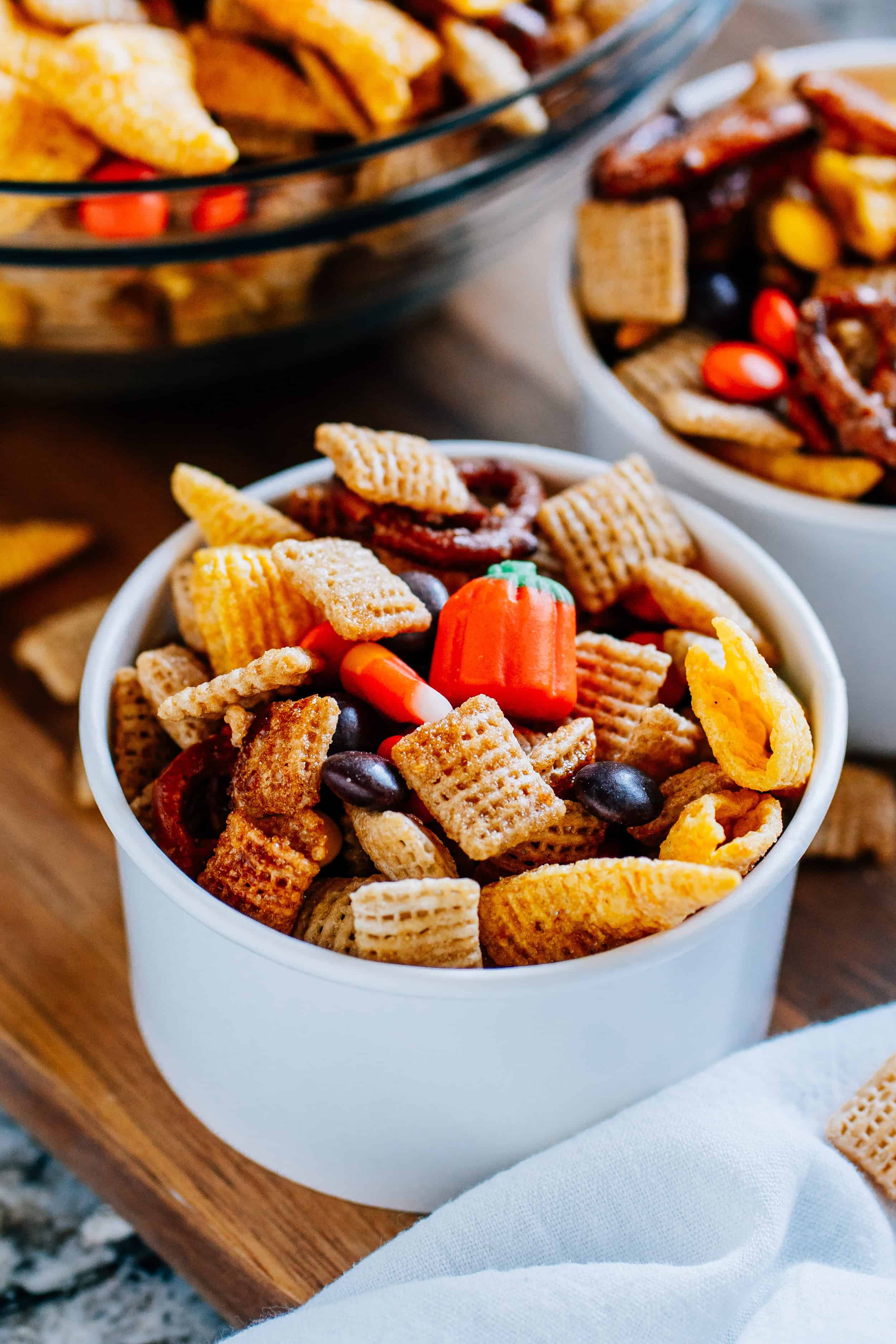 Simple, sweet and salty fall snack mix with rice squares, Bugles, pretzel twists, candy corn, candy pumpkins, and Reese's Pieces in a single serving size paper cup.