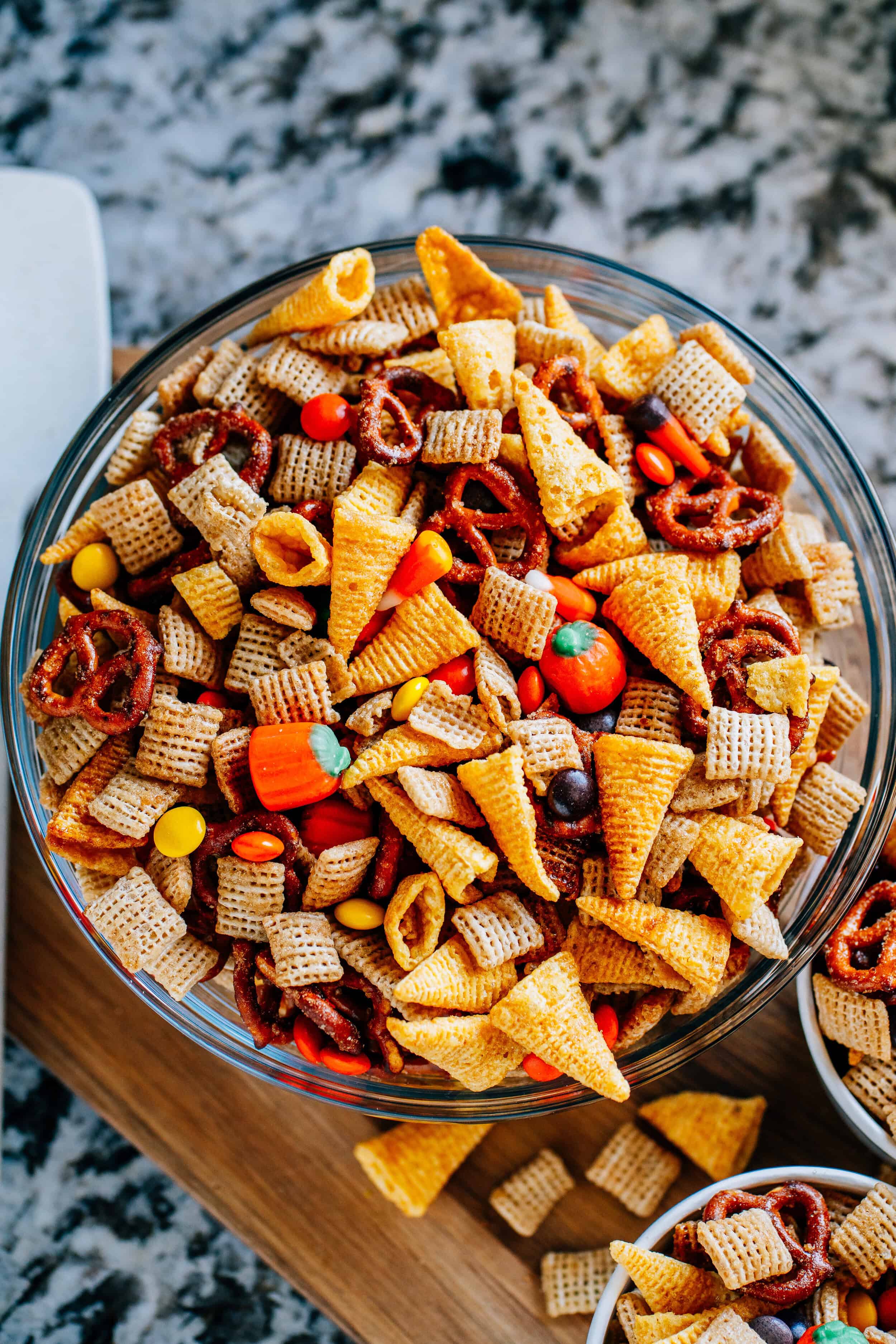 Simple, sweet and salty fall snack mix with rice squares, Bugles, pretzel twists, candy corn, candy pumpkins, and Reese's Pieces in a single serving size paper cup.