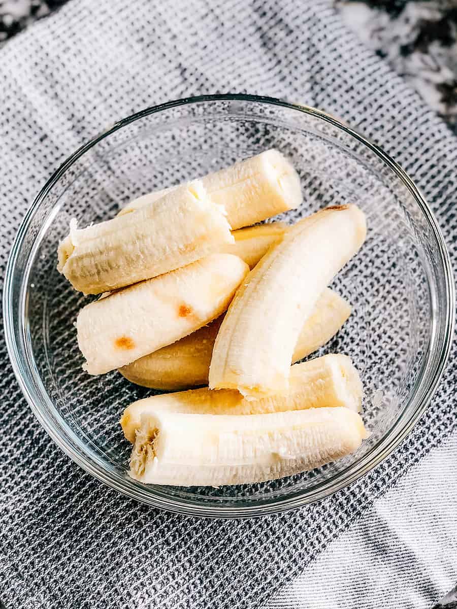 Quatre bananes mûres pelées dans un bol en verre.