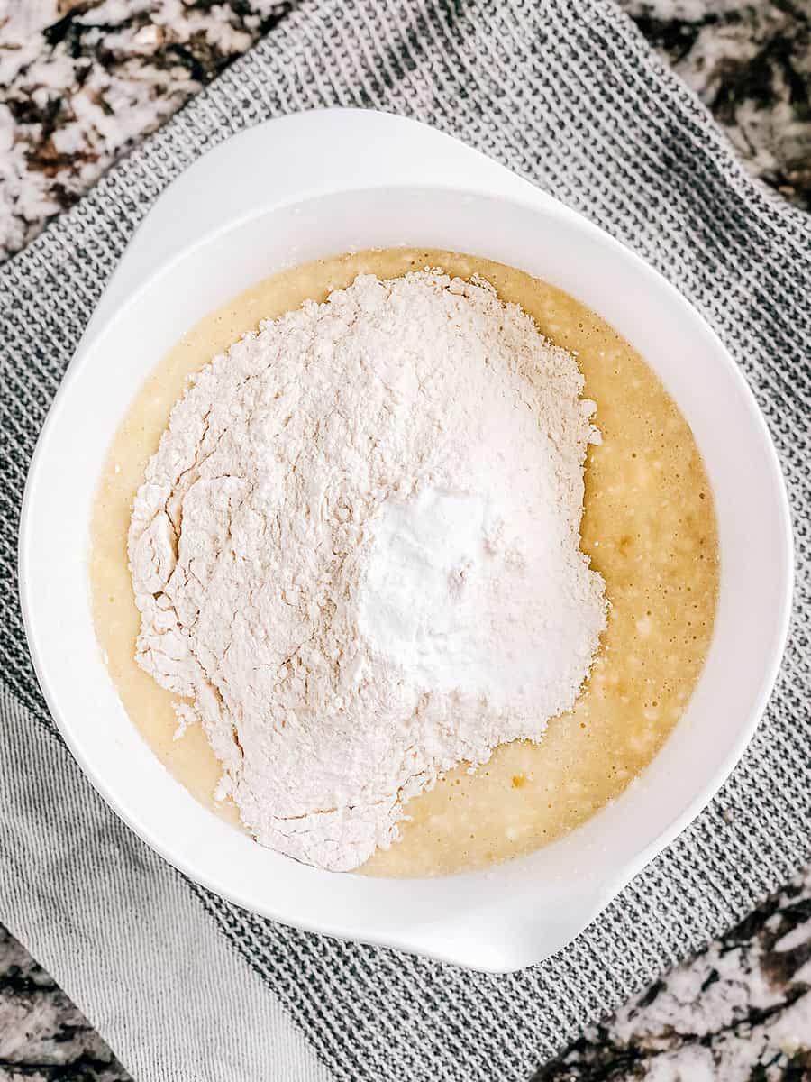 Ajout de farine, de bicarbonate de soude et de sel au mélange de bananes.