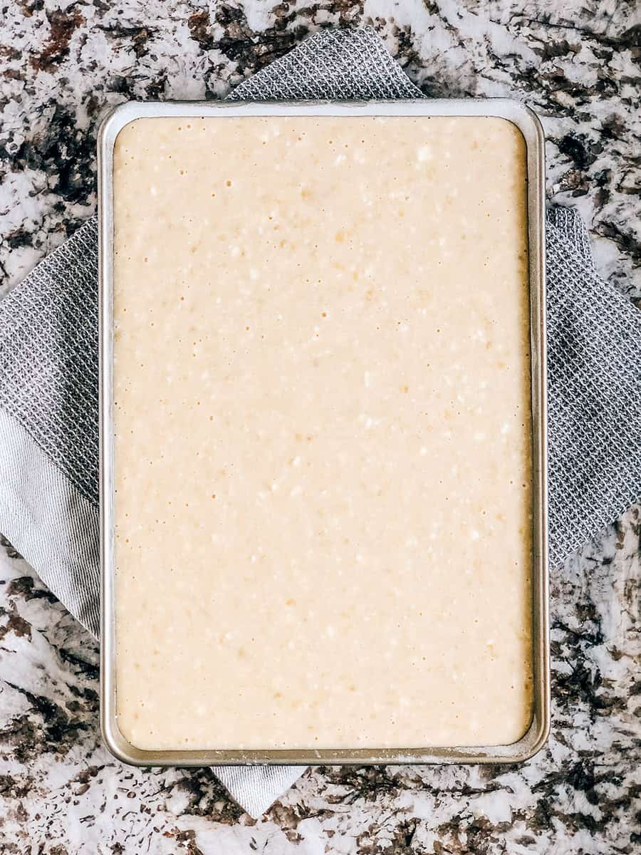 Pâte de barres de pain à la banane uniformément étalée dans une plaque de cuisson de 10x15 pouces.