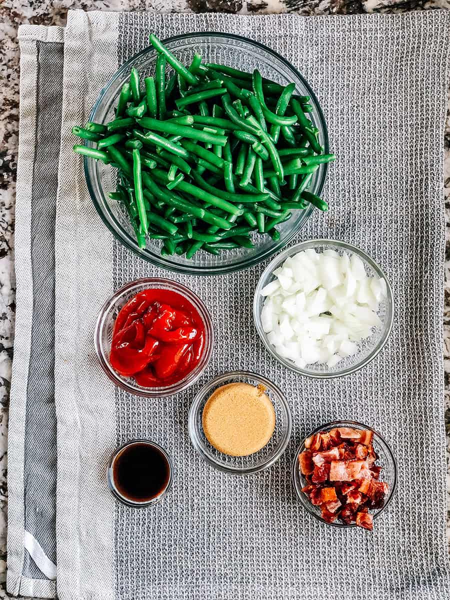 Les six ingrédients pour les haricots verts au BBQ : haricots verts égouttés, ketchup, sucre brun, sauce Worcestershire, bacon cuit et oignons.