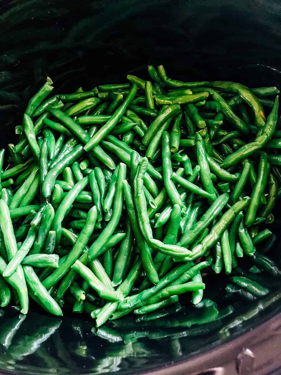 Haricots verts égouttés en couches au fond d'un autocuiseur.