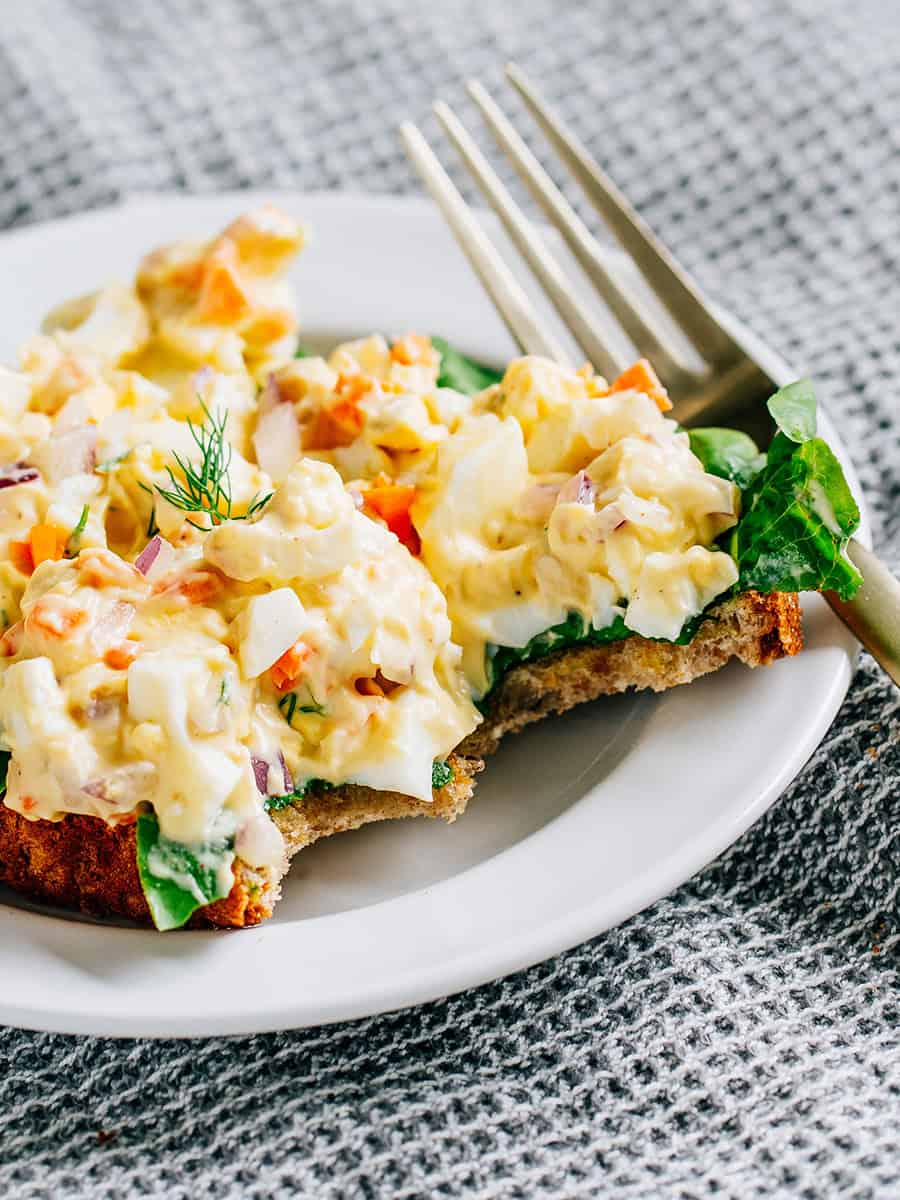 Salade d'œufs sur du pain de blé beurré et de la laitue de jardin, avec des morceaux pris.