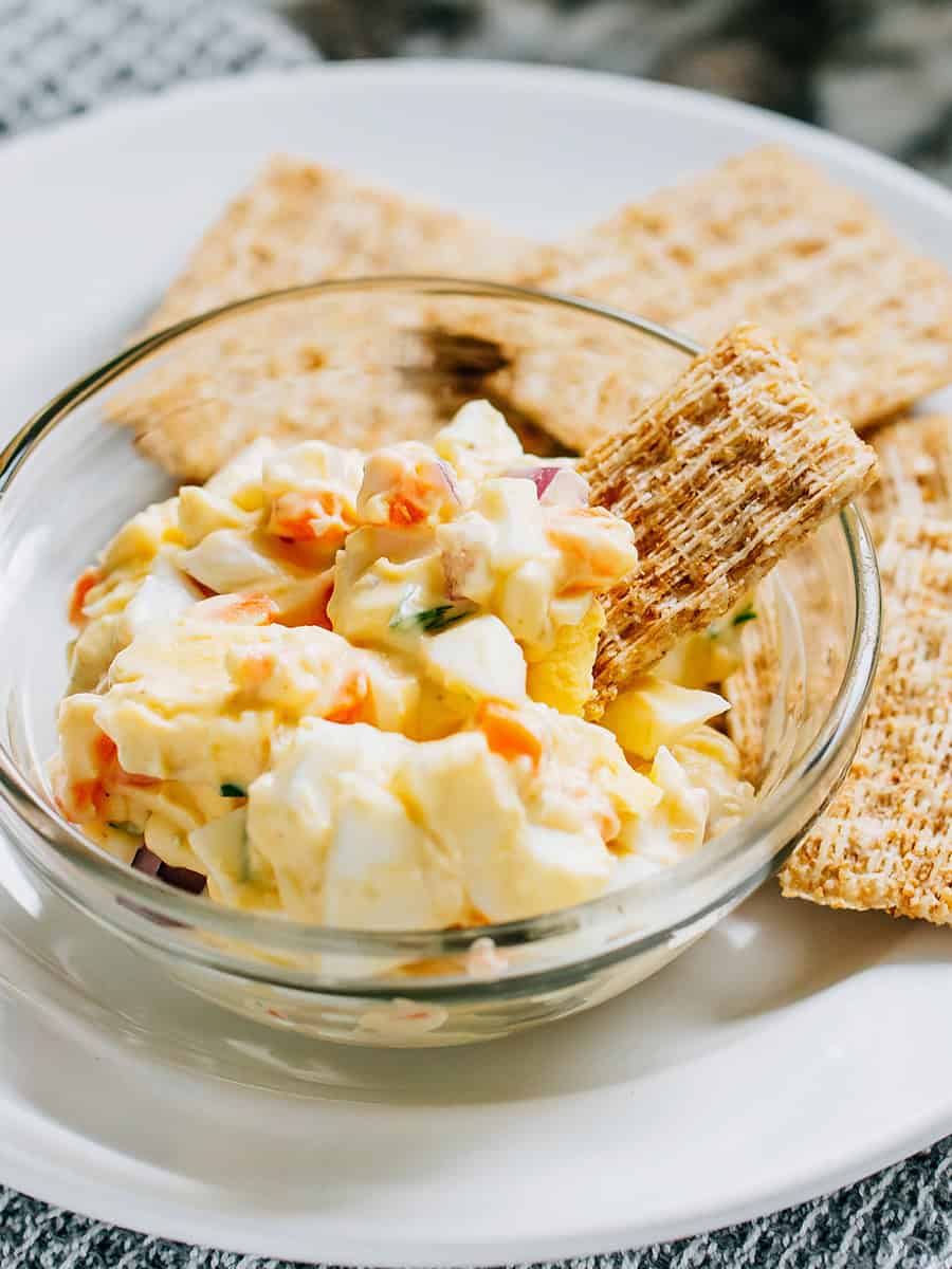 Une triscuit trempant dans la salade d'œufs pour le parfait en-cas d'été.