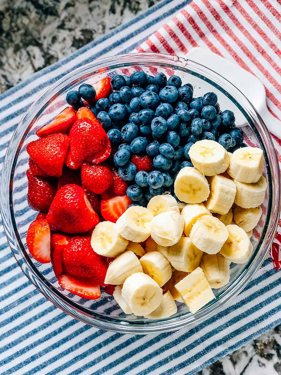 Fraises, bleuets et bananes fraîchement lavés et coupés dans le bol de salade de fruits.