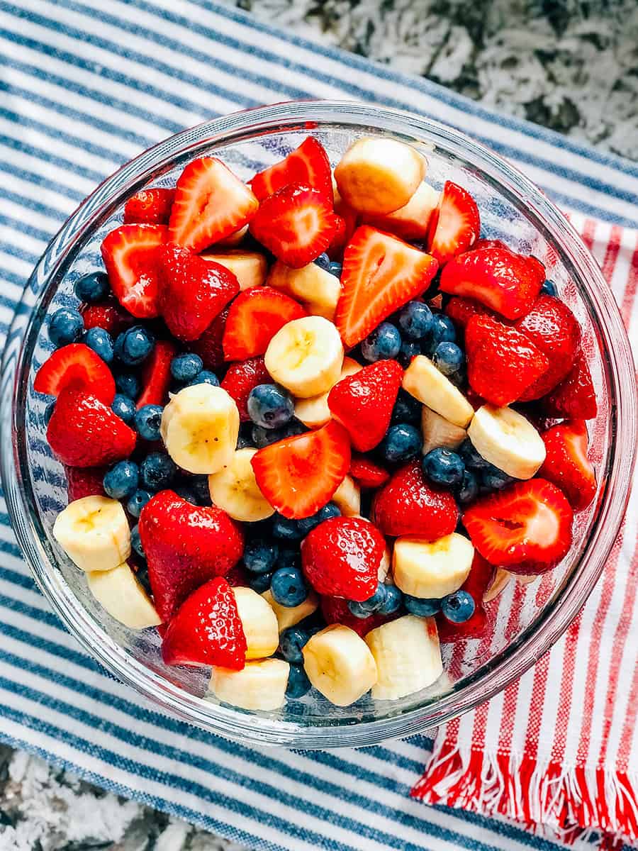 Salade de fruits complètement mélangée de fraises, bleuets et bananes enrobés d'une vinaigrette au miel et à la lime.