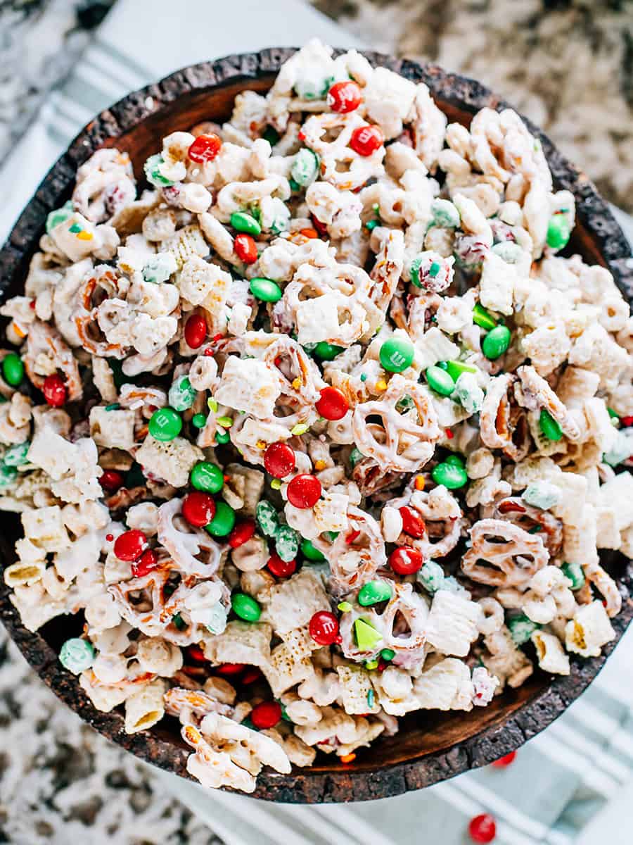 Bretzels enrobés de chocolat blanc, carrés de riz et Cheerios mélangés avec des M&Ms et des paillettes de Noël pour un en-cas amusant lors de votre fête de Noël !