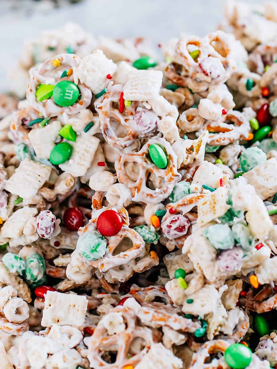 Bretzels enrobés de chocolat blanc, carrés de riz et Cheerios mélangés avec des M&Ms et des paillettes de Noël pour un en-cas amusant que les enfants adorent !