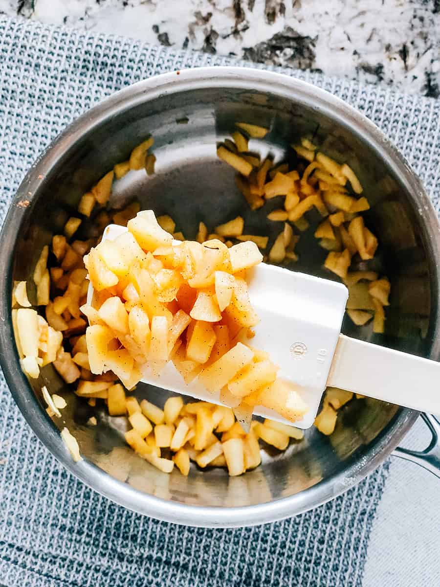 Pommes cuites, épluchées et coupées en dés avec de la cannelle dans une petite casserole.