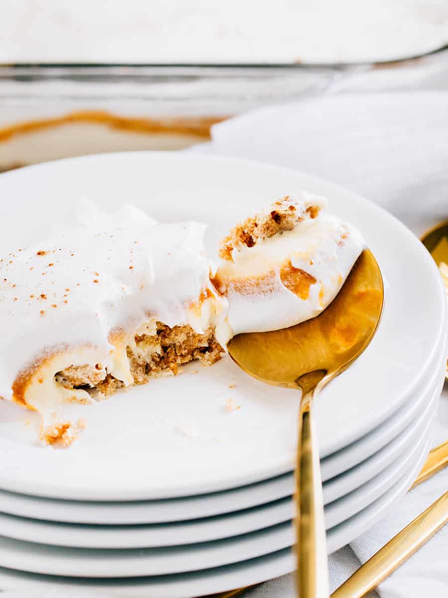 Des couches d'une croûte simple en miettes de biscuits graham, cheesecake, garniture de tarte à la citrouille et topping Cool Whip, ce délice de cheesecake à la citrouille sans cuisson est montré sur une cuillère.