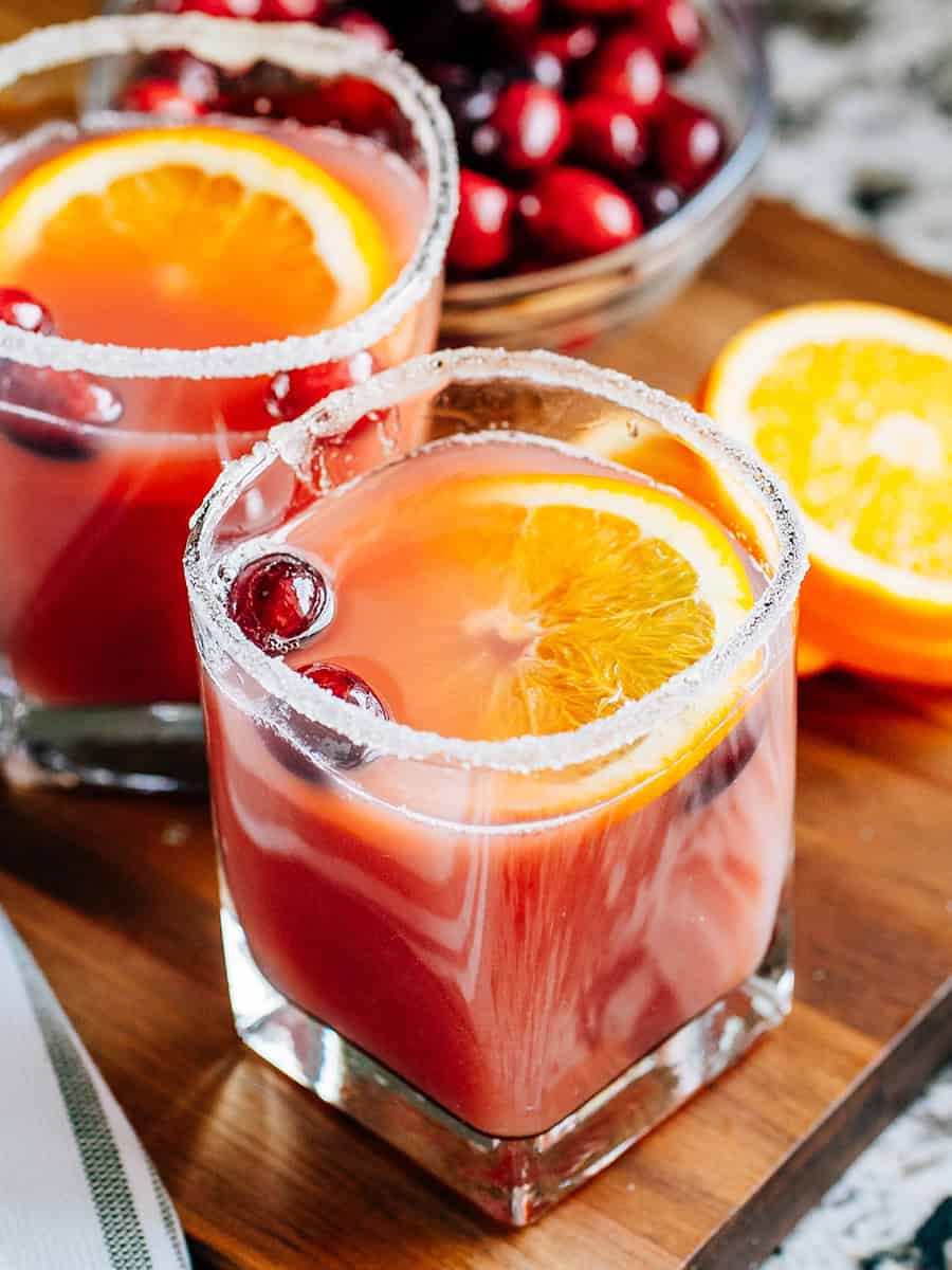 Un verre de punch à l'orange et à la canneberge avec du jus d'ananas et de la ginger ale dans un verre décoré de sucre.