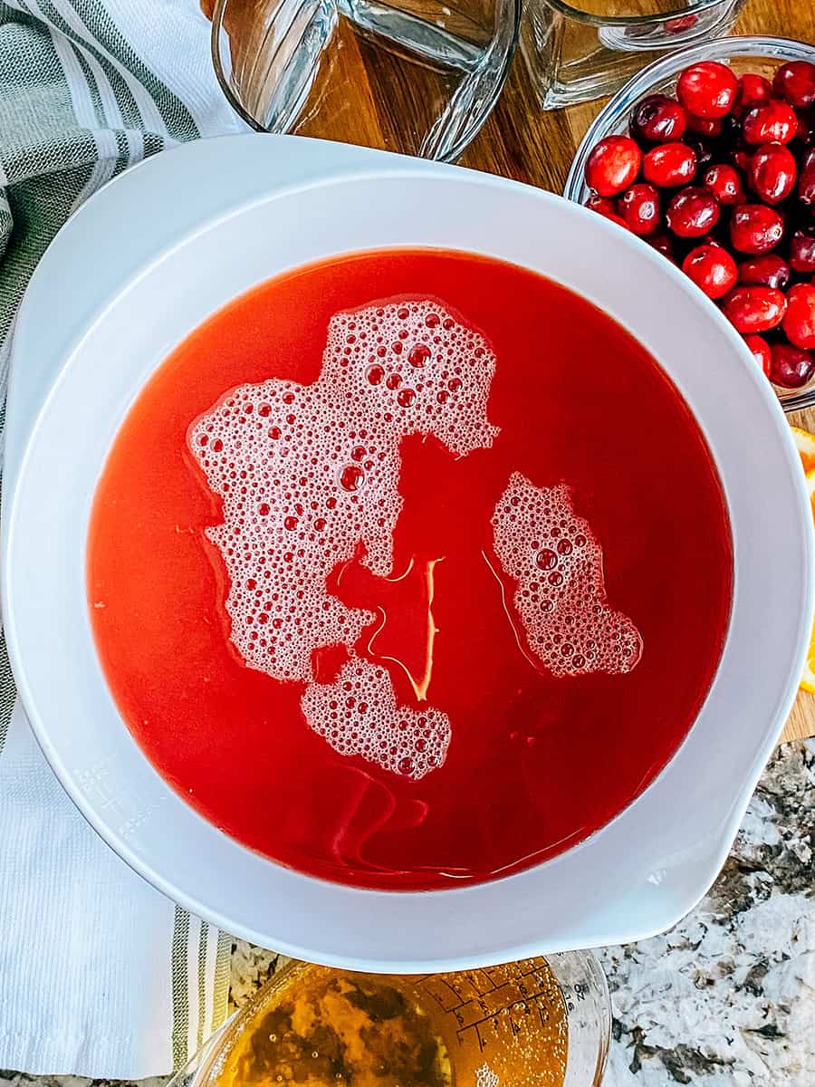 Canneberges, ananas et jus d'orange dans un grand bol de mélange pour le punch de Noël.