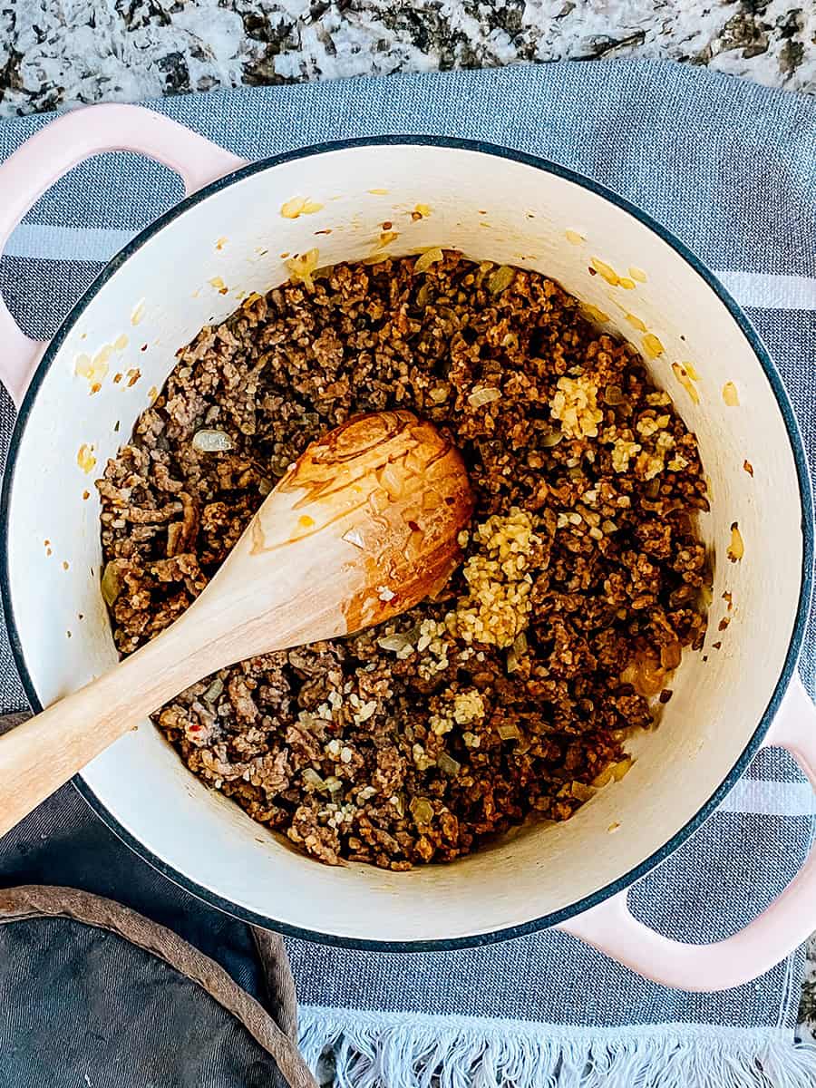 Saucisse et oignons cuits avec de l'ail haché sur le dessus dans une grande casserole.