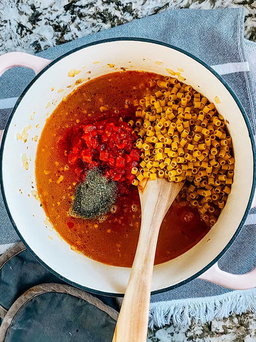 Ajoutez du bouillon, des tomates, des épices et des nouilles crues.