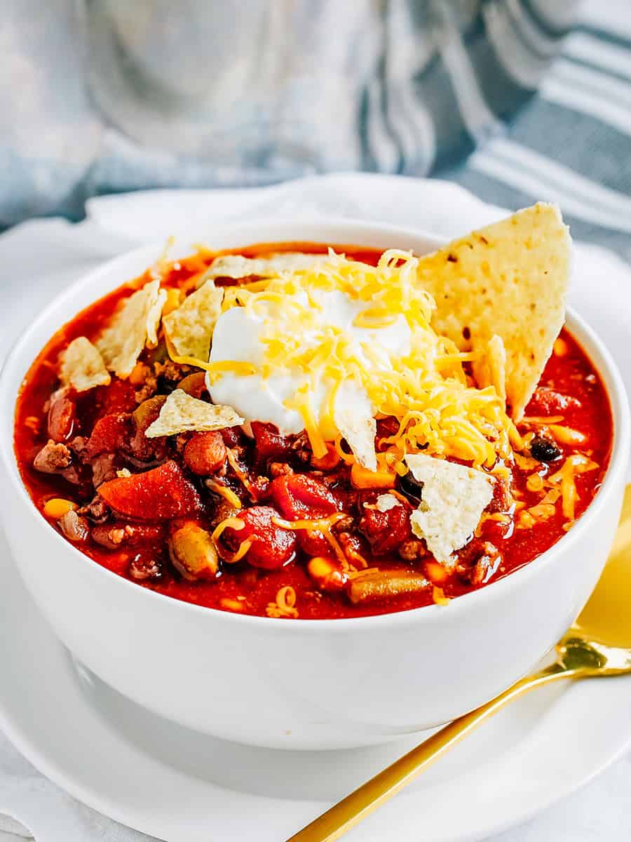 Soupe taco dans un bol garnie de crème aigre, de fromage cheddar et de chips de tortilla écrasées.