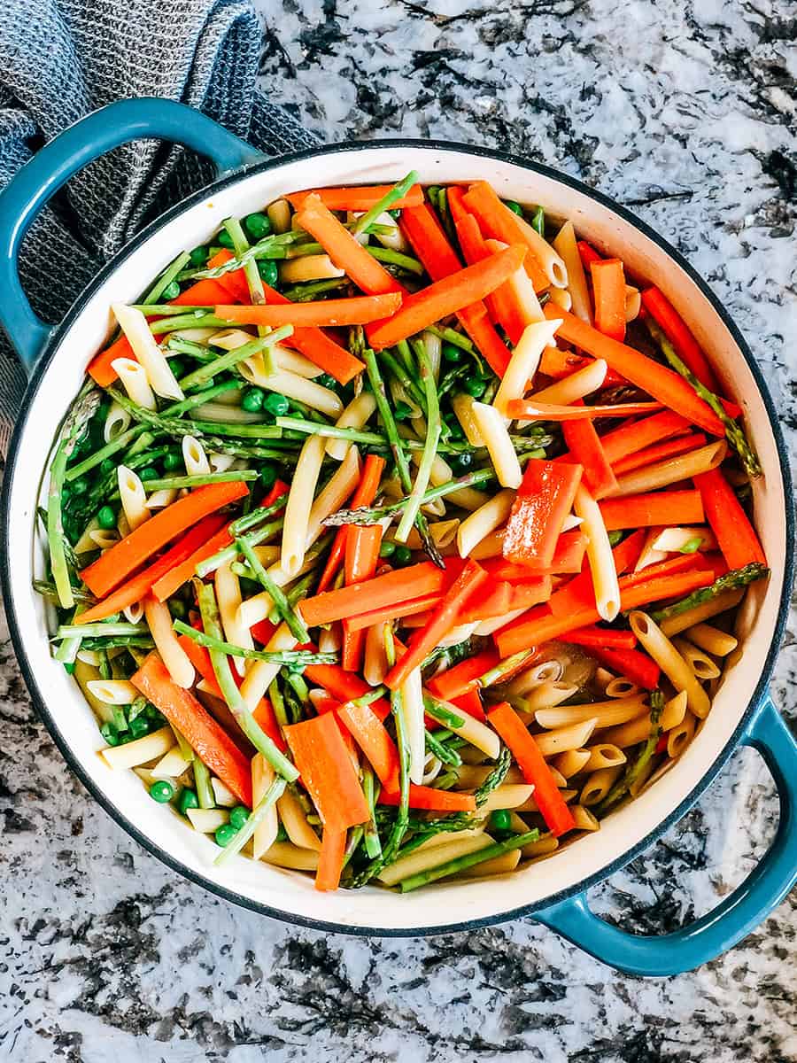 Pois, carottes et asperges mélangés aux pâtes cuites et au bouillon.