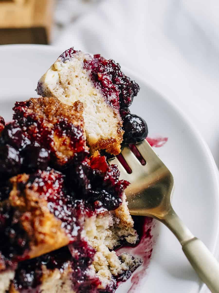 Une bouchée de casserole de pain perdu sucré à la cannelle avec une compote de bleuets maison sur le dessus.