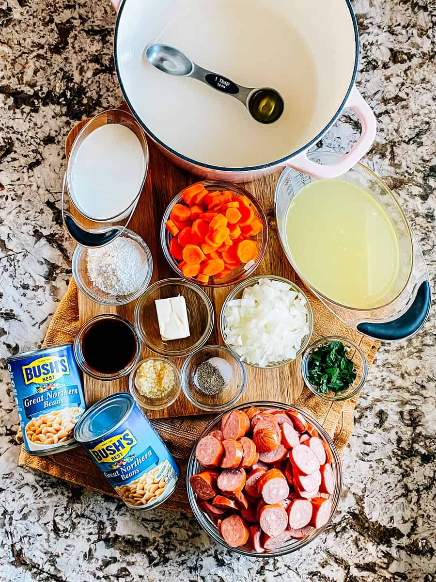 Ingrédients pour la soupe crémeuse de kielbasa et haricots sur un comptoir et une planche à découper.