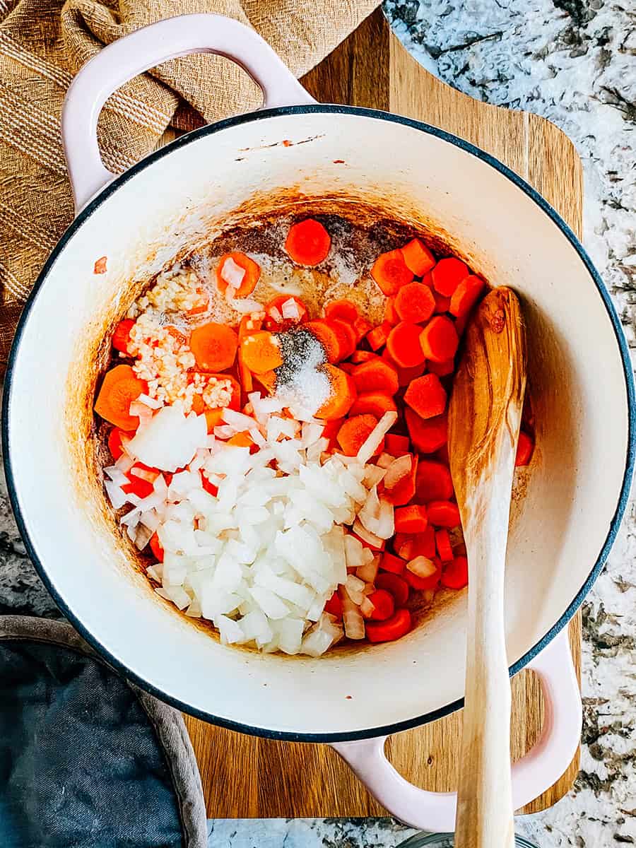 Étape trois : Beurre fondu, ail haché, carottes coupées et oignons hachés dans une casserole.