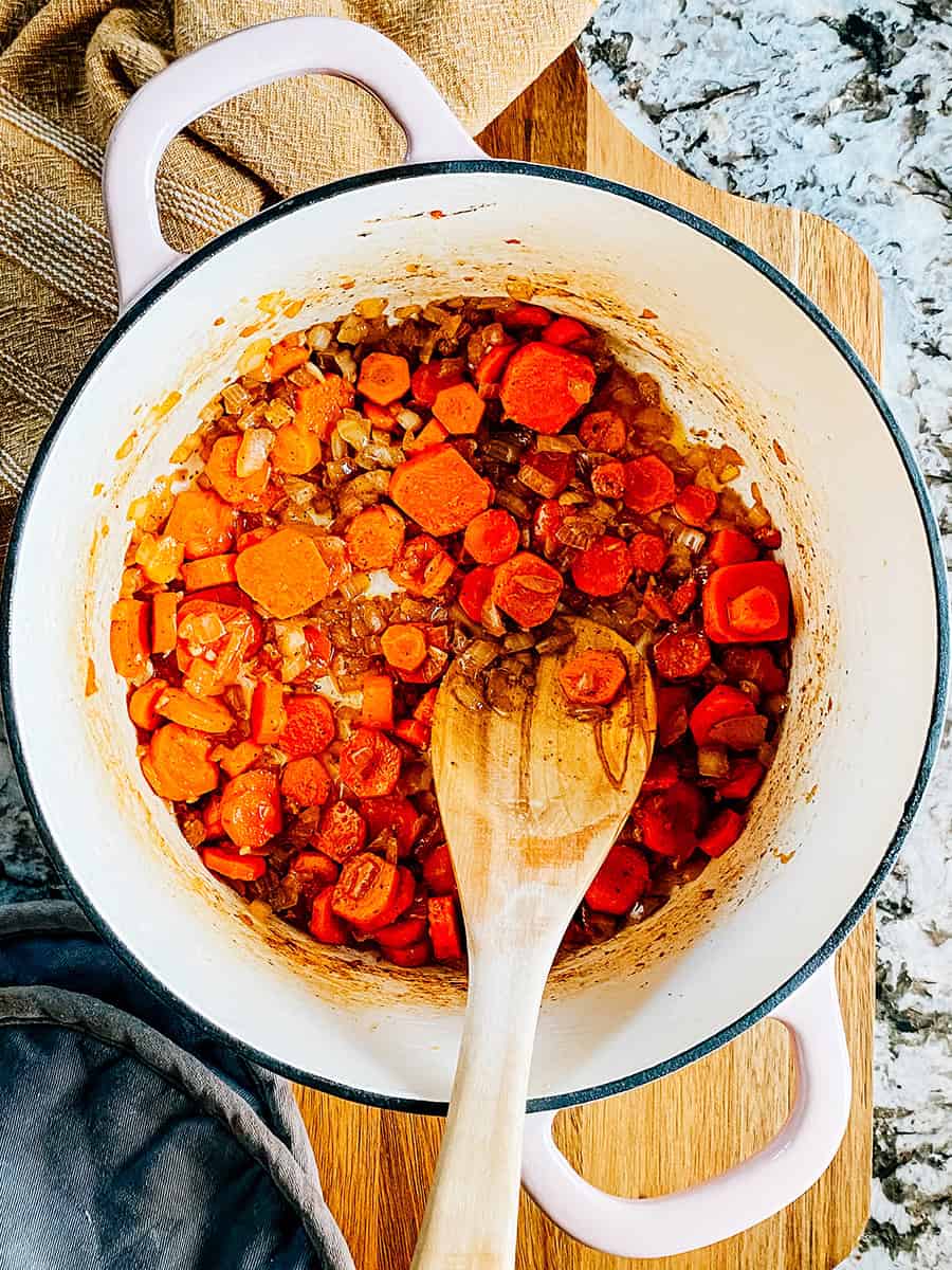 Étape cinq : Mélange de beurre cuit, d'ail haché, de carottes coupées et d'oignons hachés jusqu'à ce que les carottes commencent juste à ramollir.