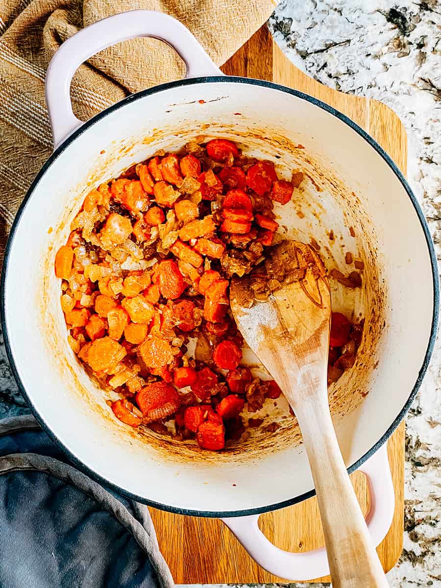 Étape sept : Ail haché cuit, carottes coupées et oignons hachés dans une casserole avec de la farine mélangée pour enrober tous les légumes cuits.