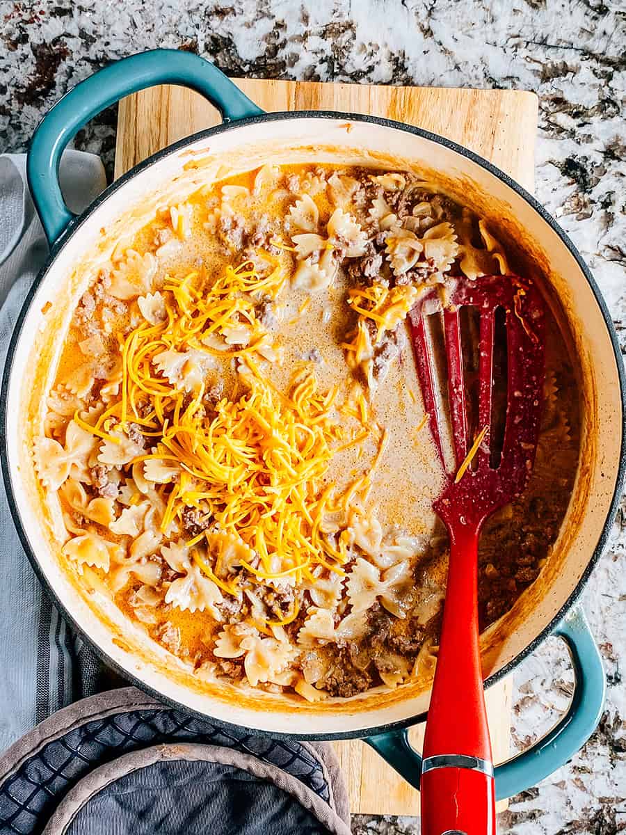 Pâtes en nœud papillon cuites avec du boeuf dans une sauce crémeuse avec du fromage cheddar râpé sur le dessus.