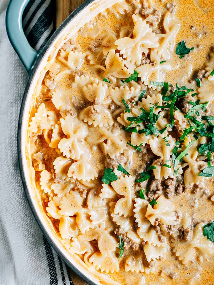 Gros plan : Un plat copieux de boeuf et de pâtes en forme de nœud papillon dans une sauce crémeuse avec du fromage cheddar fondu !