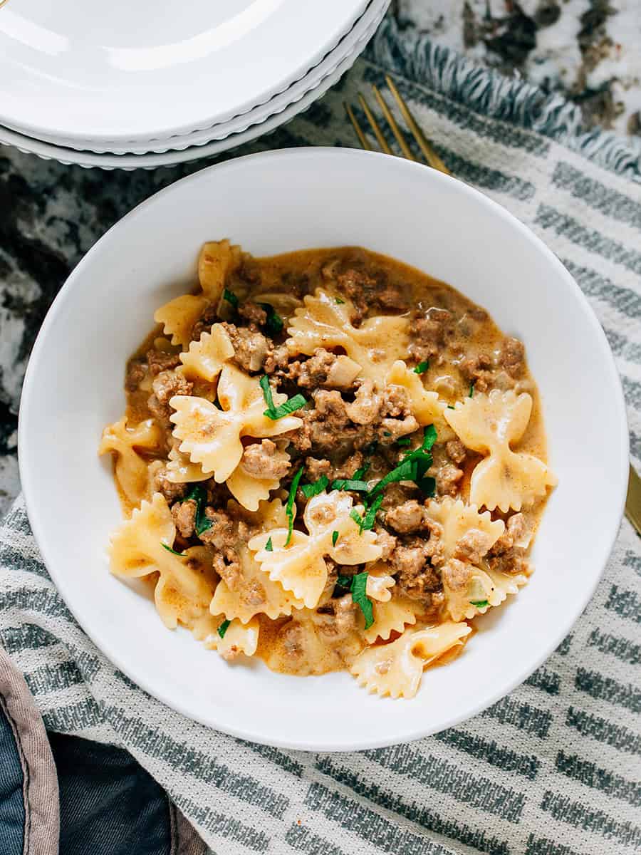 Gros plan : Un plat copieux de boeuf et de pâtes en forme de nœud papillon dans une sauce crémeuse avec du fromage cheddar fondu !