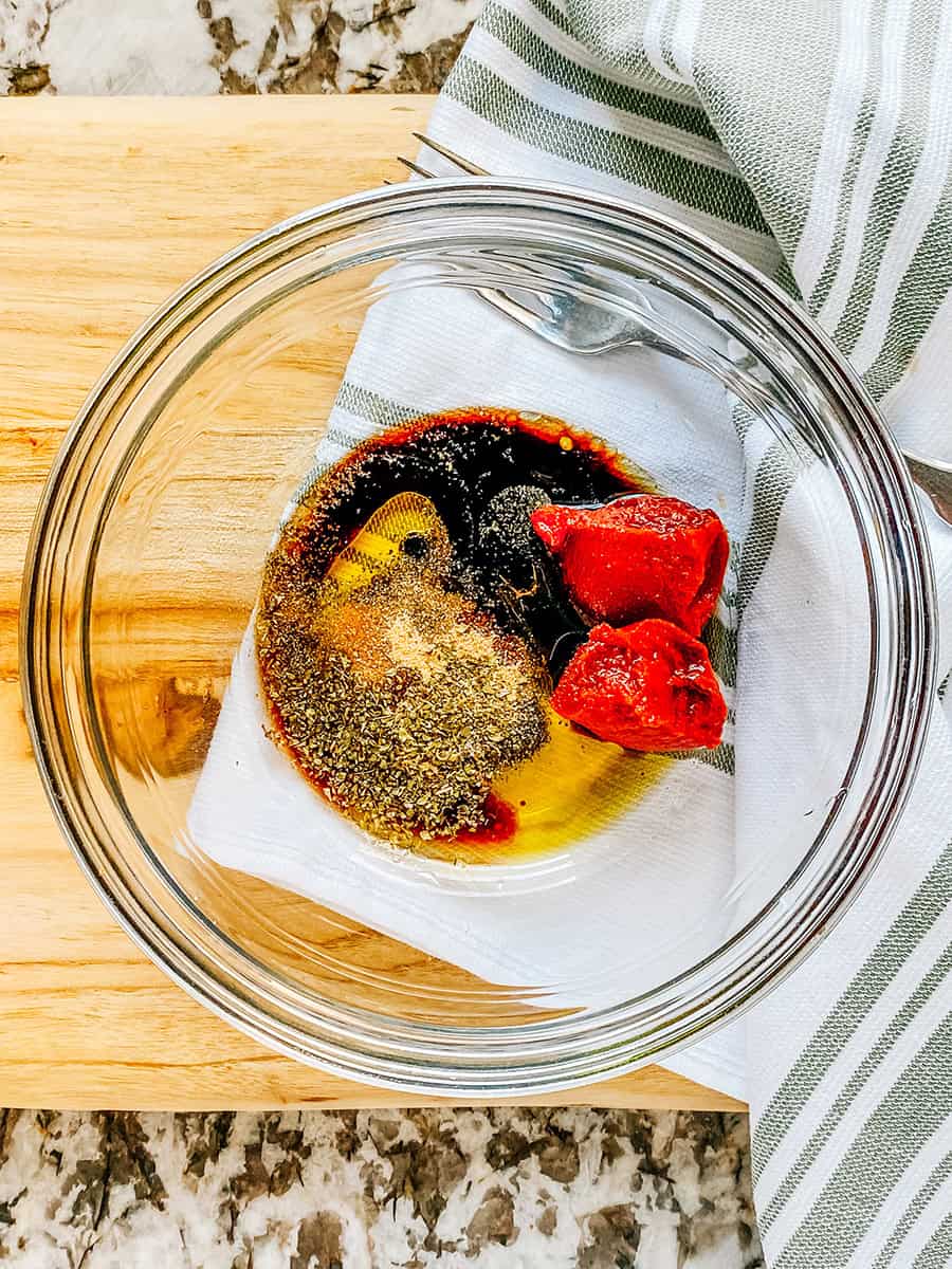 Tomato paste, balsamic vinegar, oil, and seasonings in a small glass bowl.